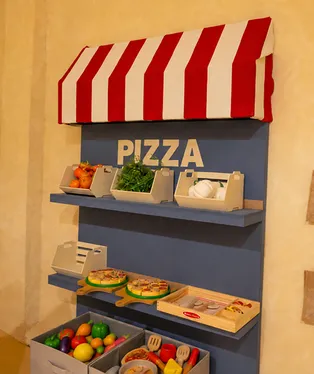 Toy pizza shop with a striped awning at Piccolitos